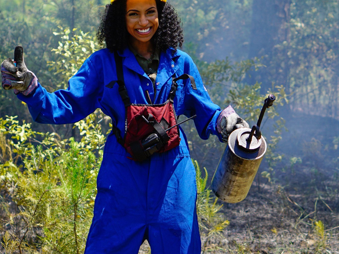 Chelsea in a hard hat and blue coveralls on location for a Georgia forestry series
