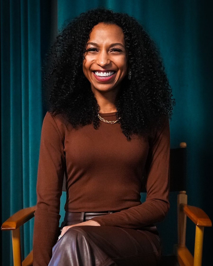 Chelsea seated in a director's chair in a studio, smiling