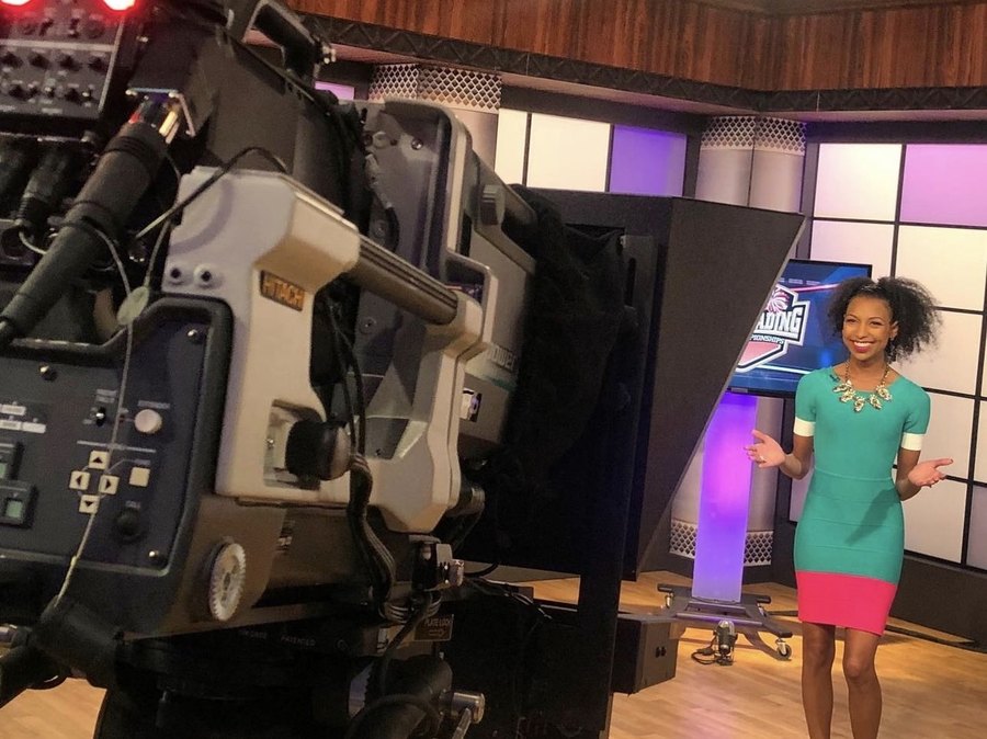 Chelsea on a TV studio set in front of a broadcast camera